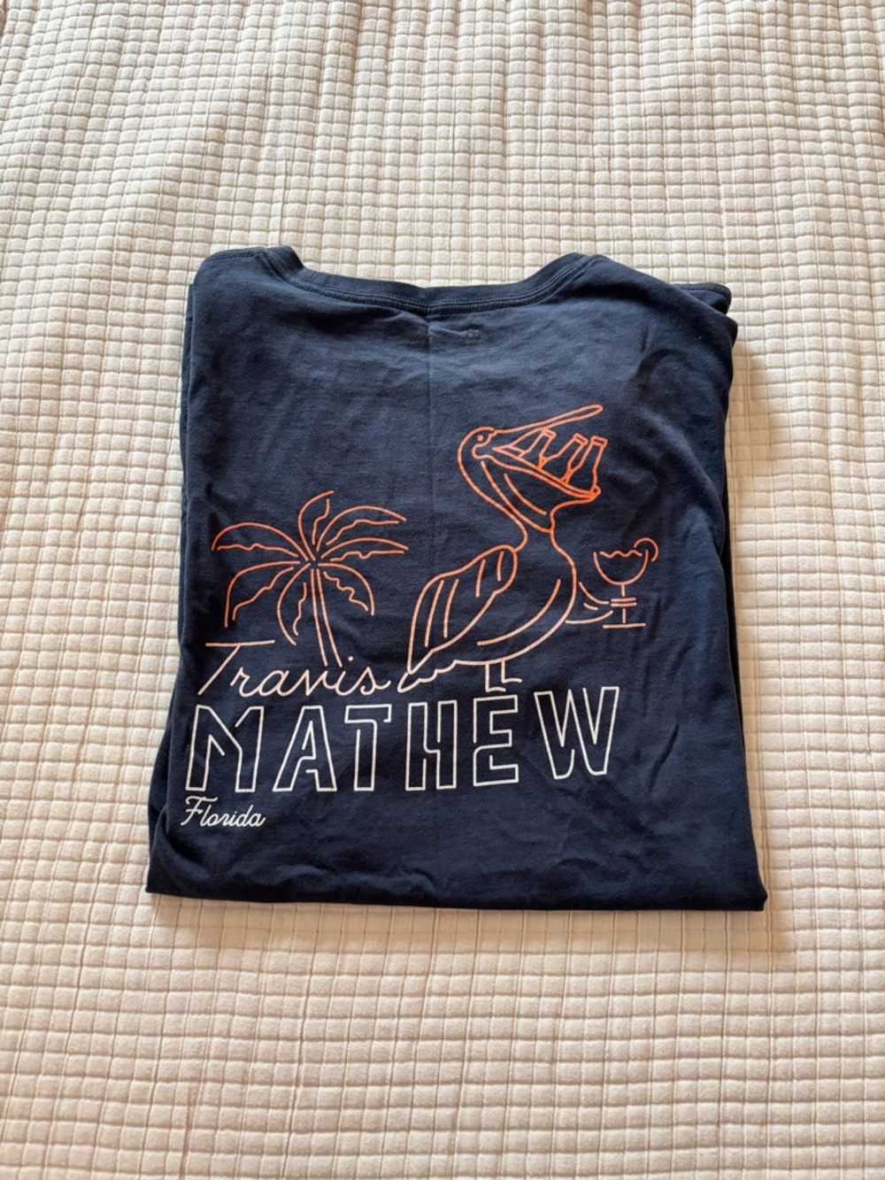Travis Mathew Navy Short Sleeve Tee with Orange and White Graphic